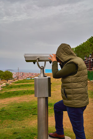 A man on an observation deck looks through a telescope.の写真素材