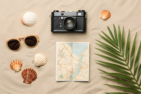 Travel background with camera, sunglasses, map and seashells on sandの素材