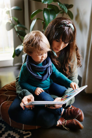 Cropped shot of a young woman reading to her son at home