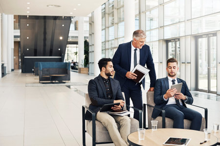 Cropped shot of three confident businessmen having a discussion while using tablets in the office...