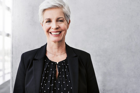 Portrait of a confident mature businesswoman standing against a grey wall