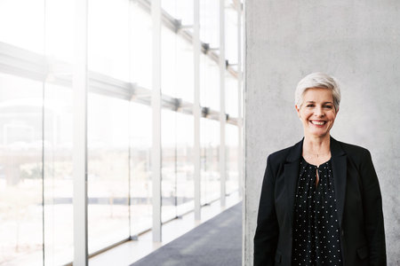 Portrait of a confident mature businesswoman standing against a grey wall