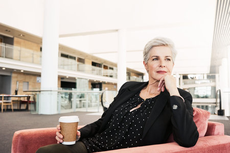 Shot of a mature businesswoman sitting on a chair in an airport lounge