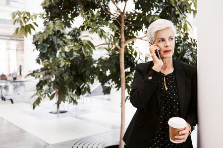 Shot of a mature businesswoman using a smartphone in a convention centerの写真素材