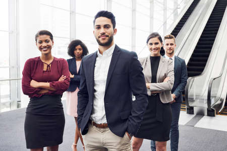 Cropped portrait of a handsome young businessman standing with his colleagues in a modern workplaceの写真素材