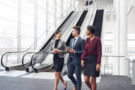 Cropped shot of a diverse group of businesspeople having a discussion while walking through a modern...