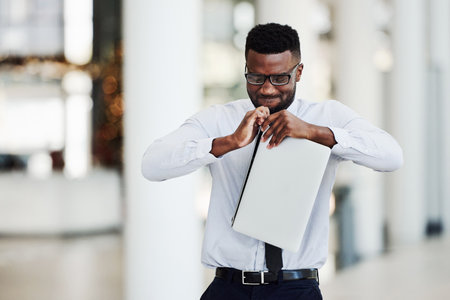 Cropped shot of a handsome young businessman feeling stressed and breaking apart his laptop in anger while in the officeの写真素材