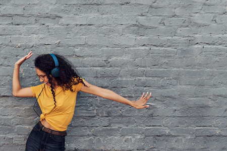 Cropped shot of an attractive young woman wearing headphones and dancing while listening to music outdoorsの写真素材