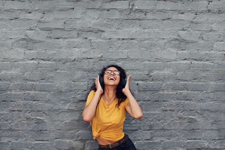 Cropped shot of an attractive young woman wearing headphones and dancing while listening to music outdoorsの写真素材