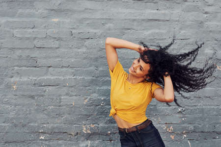 Cropped shot of an attractive young woman flipping her hair while standing alone against a gray backgroundの写真素材