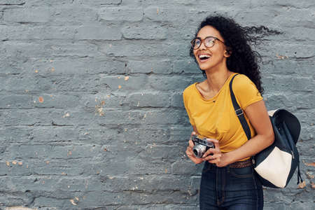 Cropped shot of an attractive young woman holding a camera and standing alone against a gray backgroundの写真素材