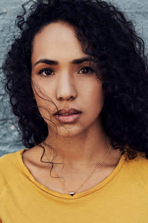Cropped portrait of an attractive young woman standing outside alone against a gray backgroundの写真素材