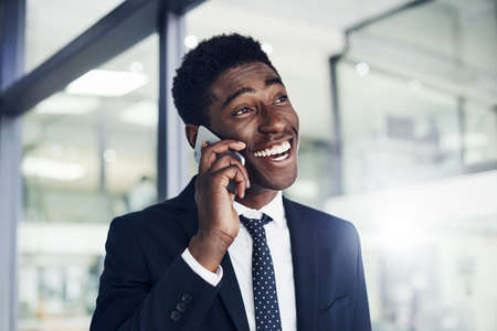 Shot of a young businessman talking on a cellphone in an officeの写真素材