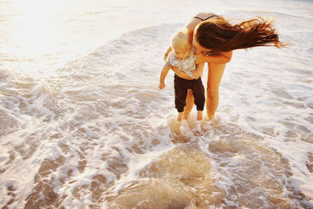 Shot of a young woman and her adorable son having fun at the beachの写真素材
