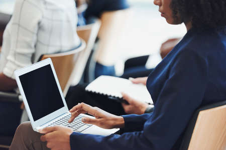 Cropped shot of a businesswoman using a laptop while attending a conferenceの写真素材