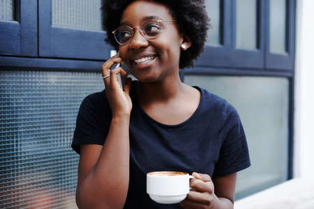 Shot of a young woman talking on her cellphone while having coffee at a cafeの写真素材