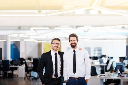 Portrait of two successful businessmen standing side by side in a modern officeの写真素材