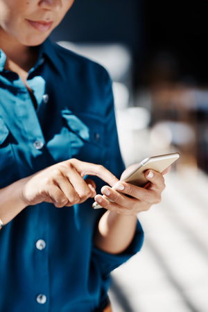 Cropped shot of a young businesswoman texting on her cellphone in an office