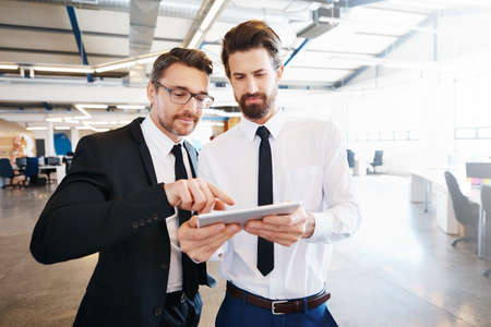 Shot of two colleagues using a digital tablet together at workの写真素材
