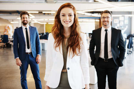 Portrait of a team of professionals standing together in a modern officeの写真素材