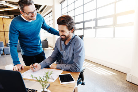 Shot of two businessmen working together on a laptop in their office