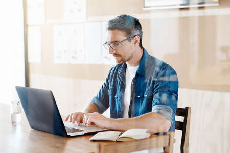 Cropped shot of a handsome designer working on his laptop in the officeの写真素材