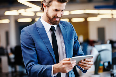 Shot of a successful young businessman using a digital tablet at work