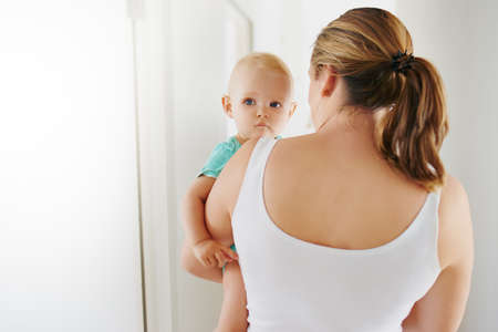 Shot of a young woman carrying her adorable baby girl at homeの写真素材