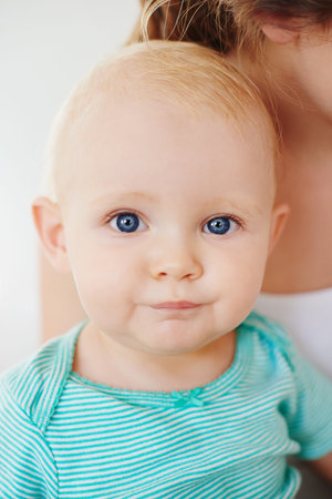 Portrait of an adorable baby girl being carried by her mother at home