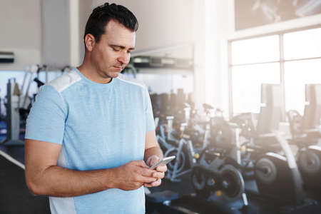 Shot of a mature man using his cellphone at the gymの写真素材