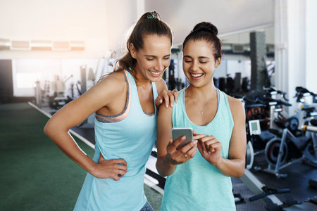 Shot of two young women using a cellphone at the gym