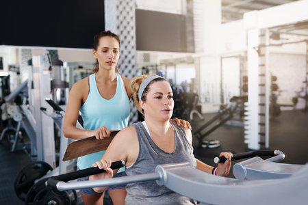 Shot of a young woman exercising at the gym with her personal trainer
