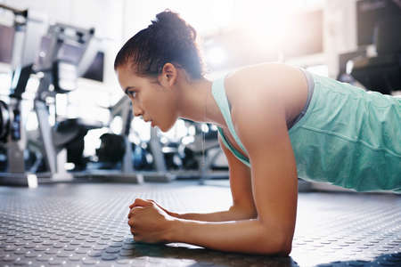 Shot of an attractive young woman doing plank exercises at the gymの写真素材