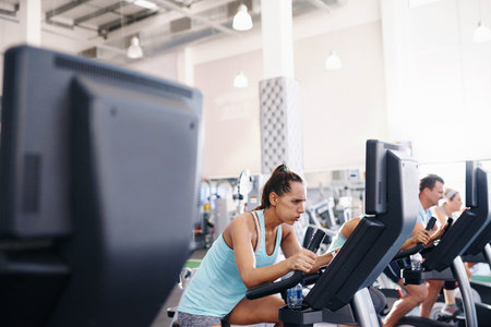 Shot of a young woman working out on an exercise bike in a gym