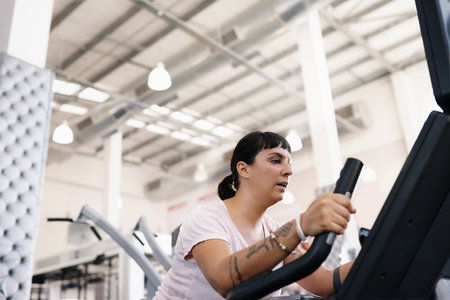 Shot of a young woman working out on an exercise bike in a gym