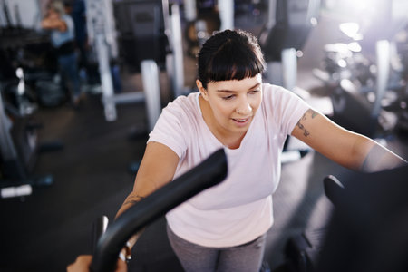 Shot of a young woman exercising on a treadmill in a gymの写真素材