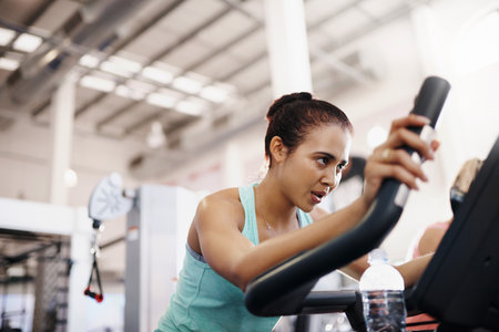 Shot of a young woman working out on an exercise bike in a gymの写真素材