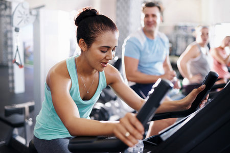 Shot of a young woman working out on an exercise bike in a gymの写真素材