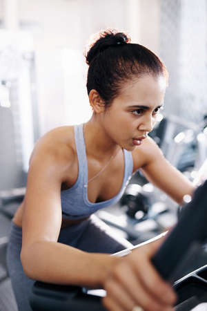 Shot of a young woman working out on an exercise bike in a gymの写真素材