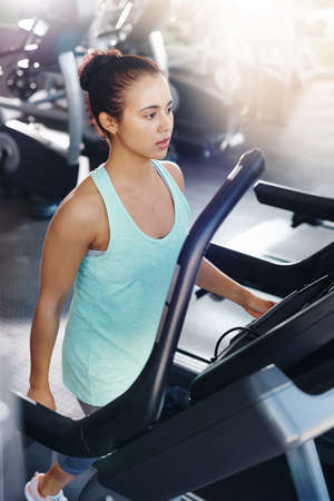 Shot of a young woman exercising on a treadmill in a gymの写真素材