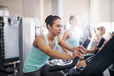 Shot of a young woman working out on an exercise bike in a gymの写真素材