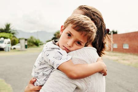Portrait of an adorable little boy hugging his mother while spending some time outdoorsの写真素材