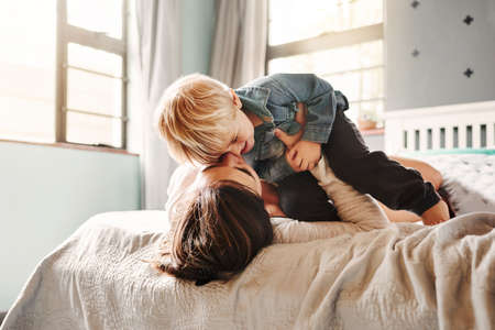 Shot of an affectionate young mother playing with her young son in the bedroom at homeの写真素材