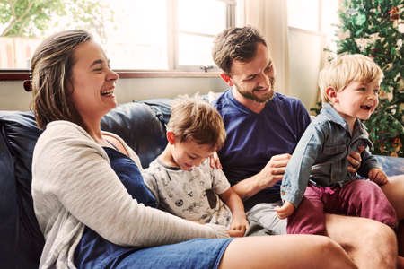 Shot of beautiful young family of four spending some quality time together in the living room at homeの写真素材