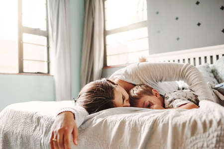 Shot of a young mother and son fast asleep in the bedroom at homeの写真素材
