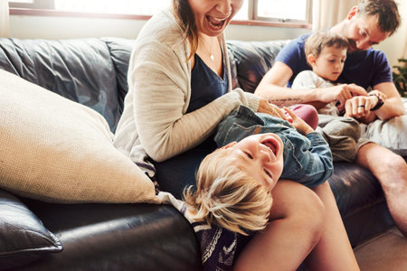 Shot of beautiful young family of four spending some quality time together in the living room at...