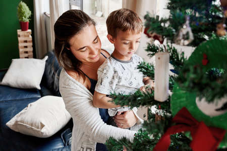 Shot of an adorable mother and son decorating a Christmas tree at homeの写真素材