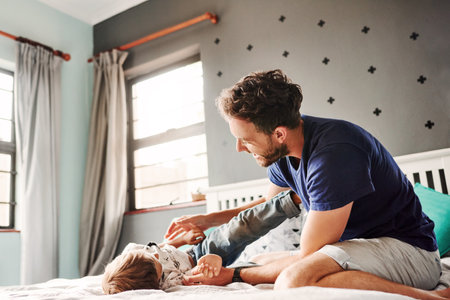 Shot of a cheerful young father and son playing together in the bedroom at homeの写真素材