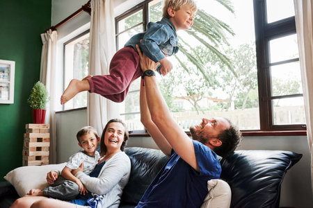 Shot of beautiful young family of four spending some quality time together in the living room at...