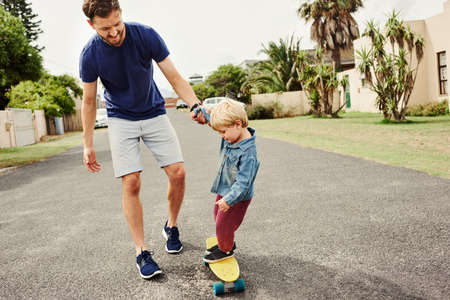 Full length shot of a cheerful young father and son skateboarding outdoorsの写真素材